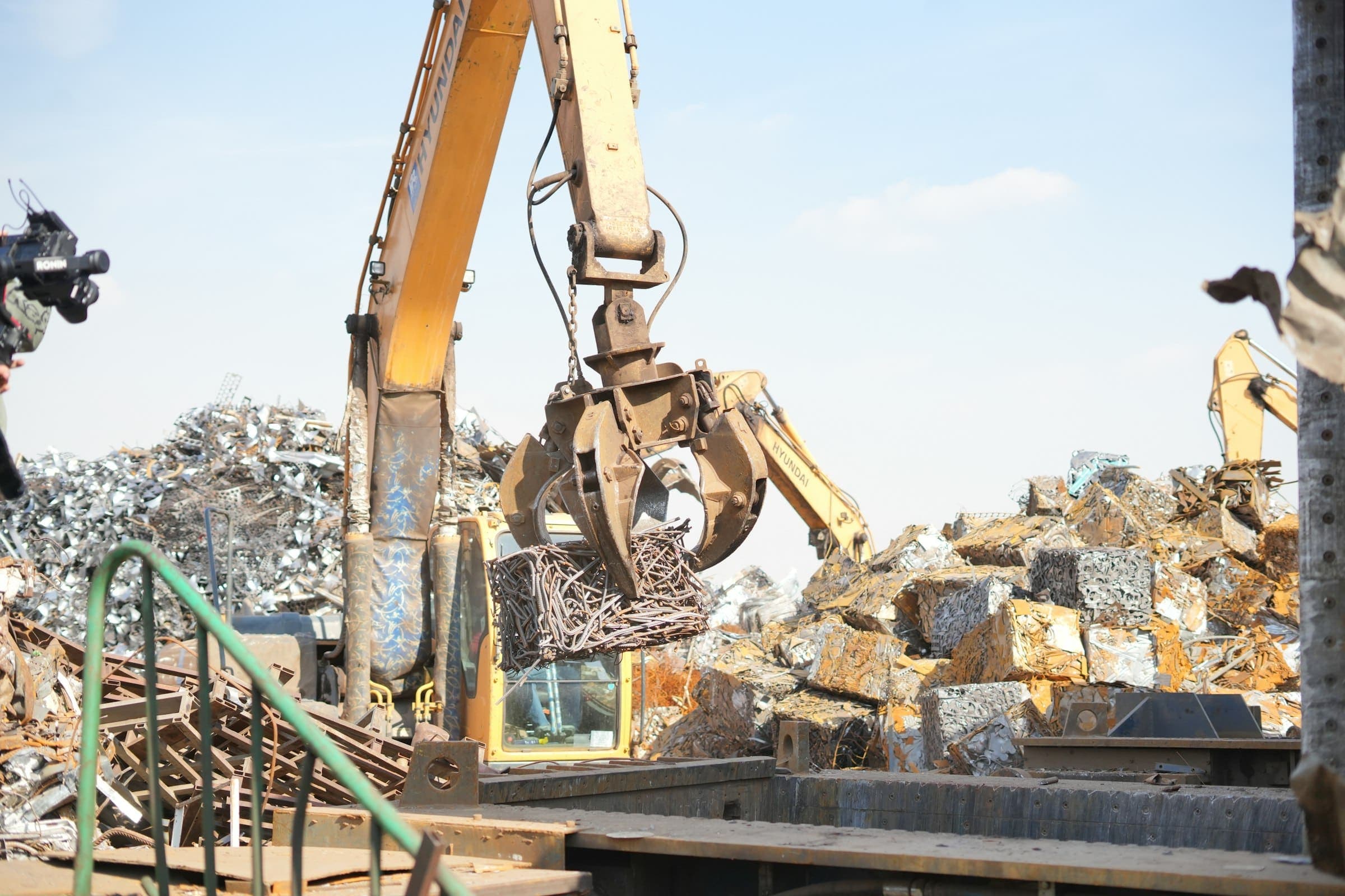 Excavator sorting scrap metal An excavator's grapple lifting a bundle of scrap metal in a scrap yard