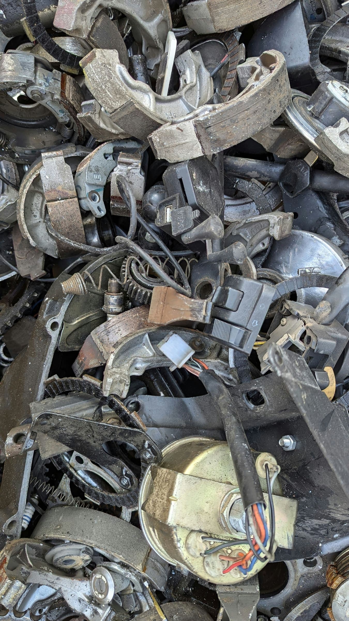 A pile of old motorbike parts, including brake shoes, switches and a speedometer A pile of old motorbike parts, including brake shoes, switches and a speedometer